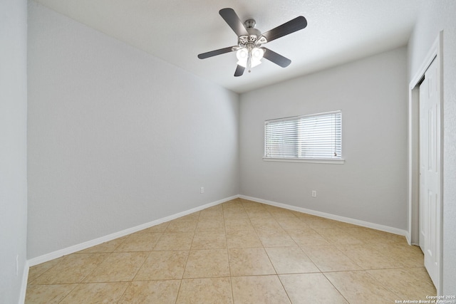 unfurnished bedroom with tile patterned floors, a ceiling fan, baseboards, and a closet