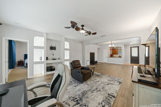 office area featuring light wood-style flooring, visible vents, baseboards, and ceiling fan with notable chandelier