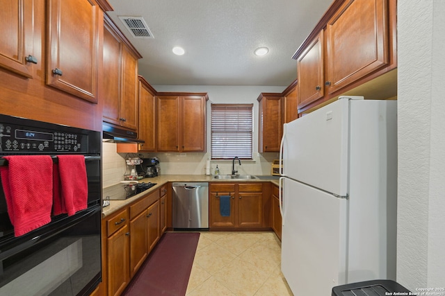 kitchen featuring under cabinet range hood, backsplash, visible vents, a sink, and black appliances