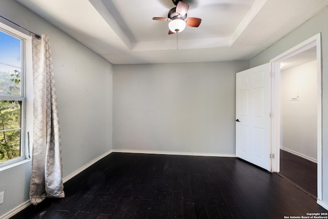 unfurnished bedroom with a ceiling fan, baseboards, wood-type flooring, and a tray ceiling