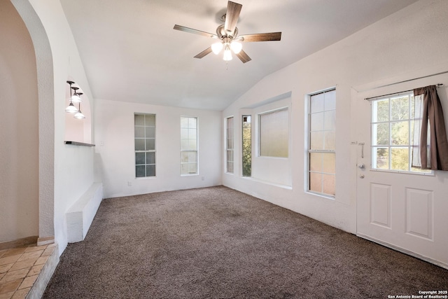 unfurnished room featuring a ceiling fan, arched walkways, vaulted ceiling, and carpet