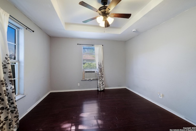 spare room with ceiling fan, wood finished floors, a raised ceiling, baseboards, and cooling unit