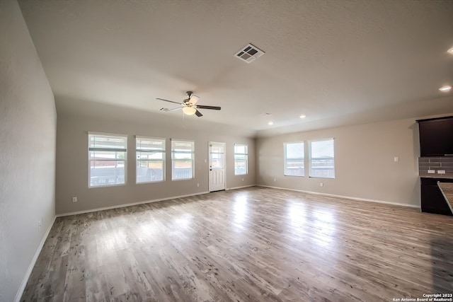 unfurnished living room with baseboards, a ceiling fan, wood finished floors, and visible vents
