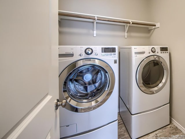 laundry area with separate washer and dryer, light wood-style floors, and laundry area