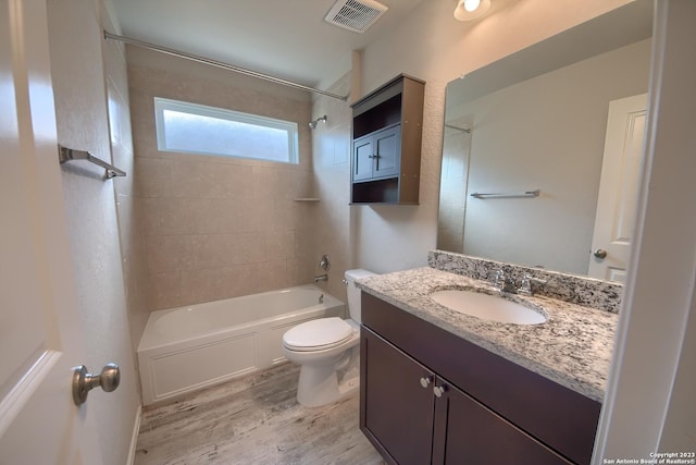 bathroom with bathing tub / shower combination, wood finished floors, visible vents, toilet, and vanity