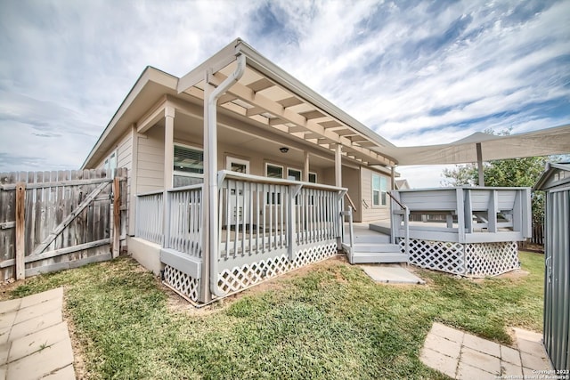 rear view of property with a wooden deck, fence, and a yard