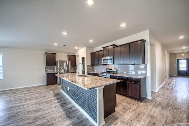 kitchen featuring light wood finished floors, dark brown cabinetry, stainless steel appliances, and a sink