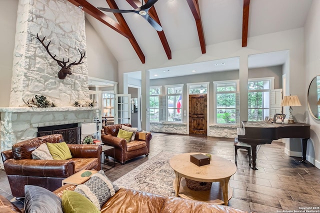 living area featuring beamed ceiling, plenty of natural light, a fireplace, and ceiling fan
