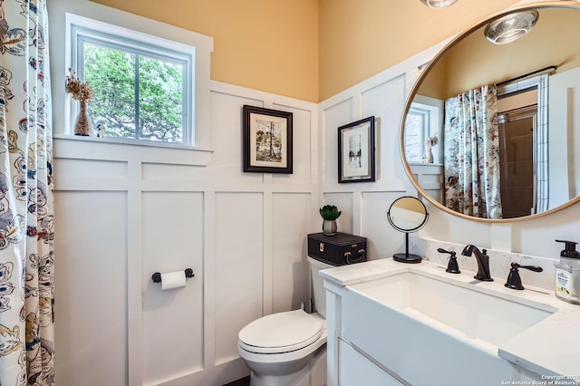 full bathroom featuring a shower with curtain, toilet, vanity, and a decorative wall