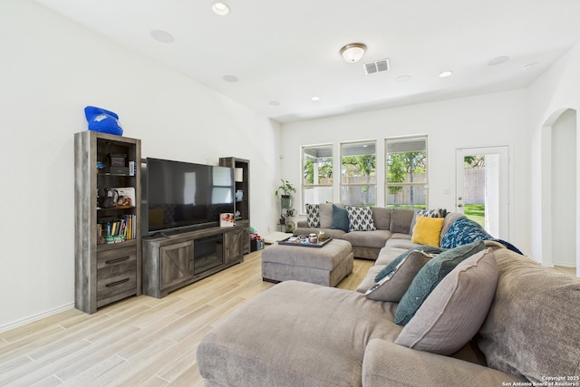 living area with light wood-style floors, arched walkways, baseboards, visible vents, and recessed lighting