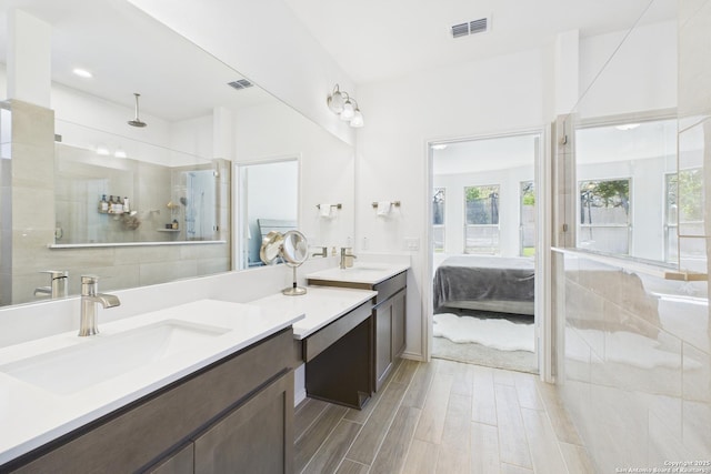 bathroom with a tile shower, a wealth of natural light, wood finished floors, and visible vents