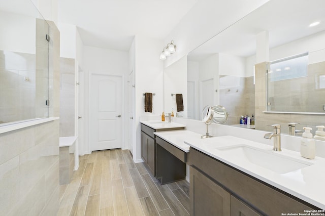 full bathroom with a tile shower, wood finished floors, and vanity