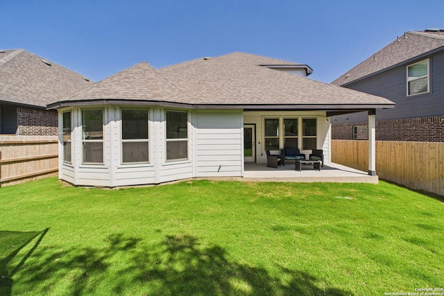 rear view of property featuring a yard, a patio area, roof with shingles, and a fenced backyard