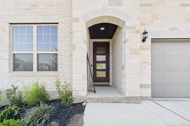 entrance to property featuring brick siding, stone siding, and a garage