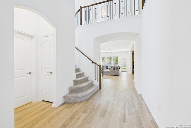 entrance foyer with arched walkways, wood finished floors, and stairs