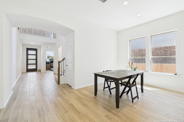 dining area with arched walkways, light wood-style flooring, baseboards, and recessed lighting