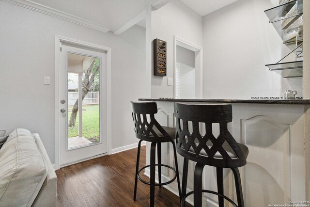 dining area with crown molding, dark wood-style floors, a dry bar, and baseboards