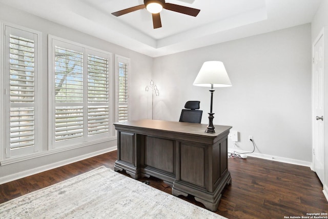 office area with a raised ceiling, a ceiling fan, baseboards, and dark wood-style floors