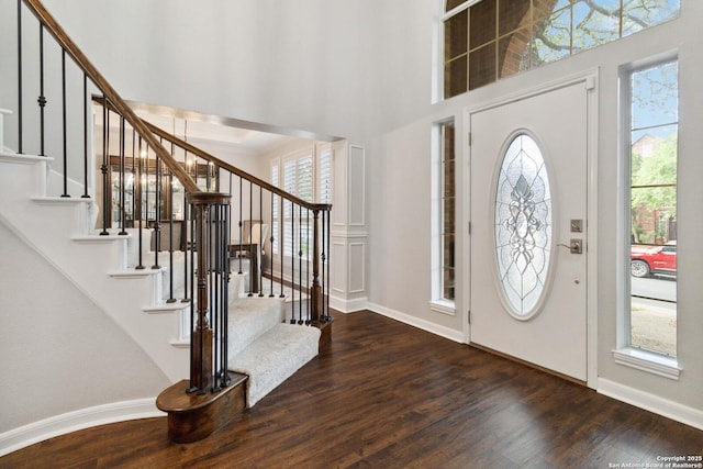 foyer entrance featuring wood finished floors, a wealth of natural light, stairs, and a high ceiling