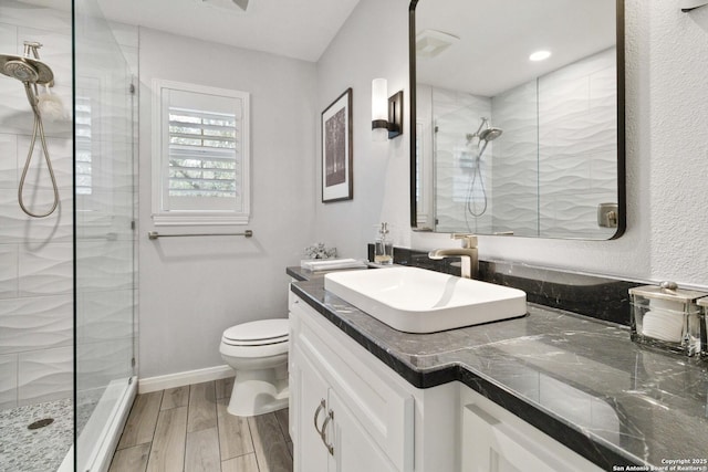 full bath with a shower stall, wood finished floors, toilet, vanity, and baseboards