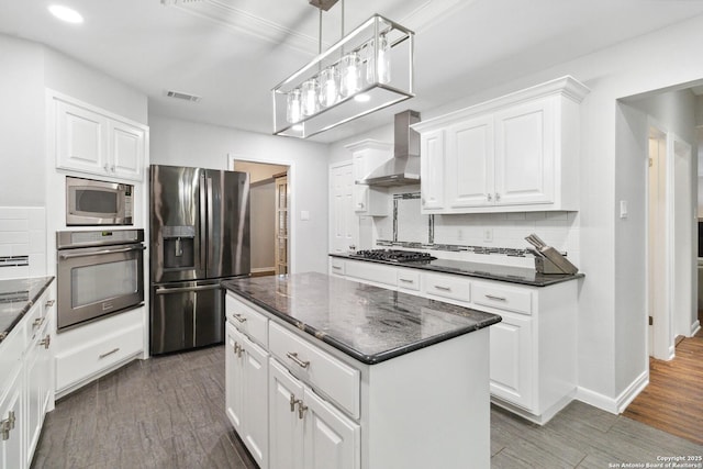 kitchen with wall chimney exhaust hood, stainless steel appliances, visible vents, and decorative backsplash