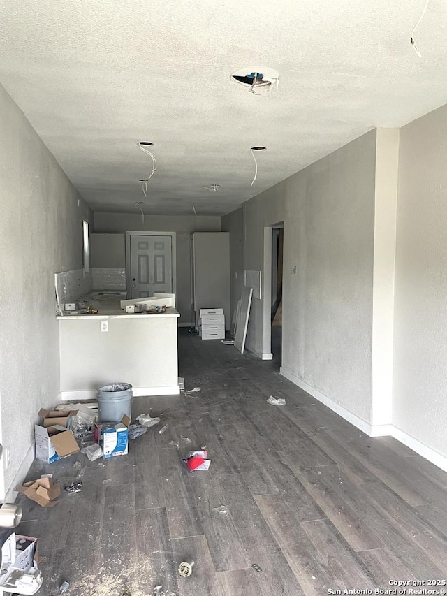 unfurnished living room with dark wood-type flooring and a textured ceiling
