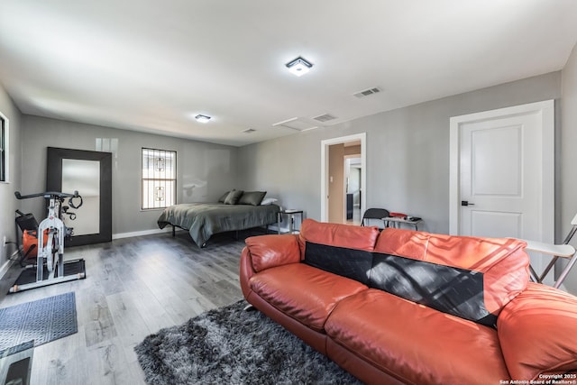 bedroom featuring attic access, wood finished floors, visible vents, and baseboards