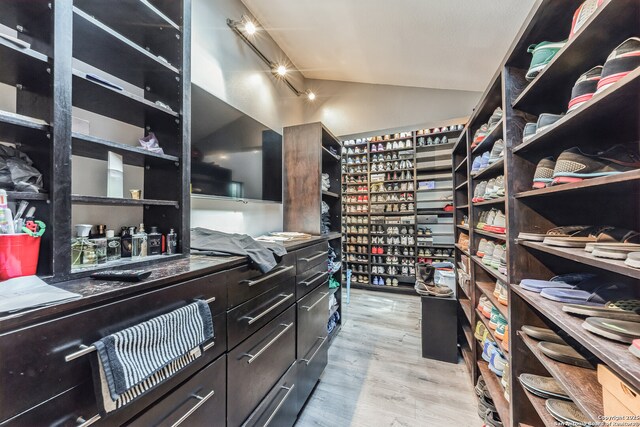 walk in closet featuring vaulted ceiling and light wood-style flooring