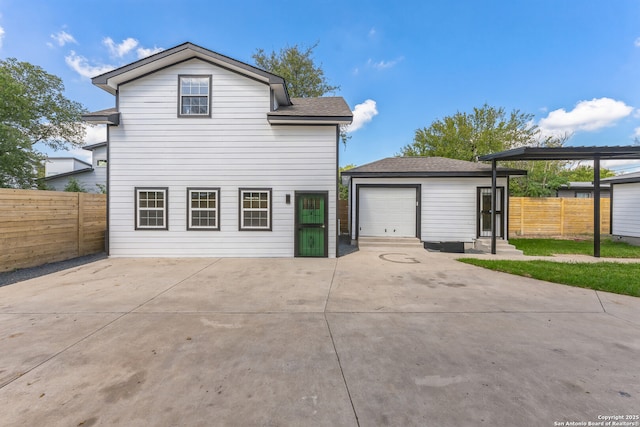 exterior space with fence, a shingled roof, driveway, and an outdoor structure