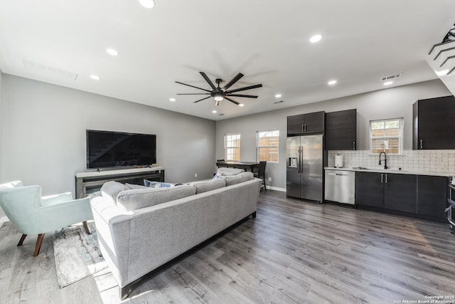 living room featuring baseboards, visible vents, recessed lighting, light wood-style floors, and a ceiling fan