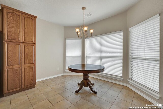 unfurnished dining area featuring visible vents, baseboards, a notable chandelier, and light tile patterned floors