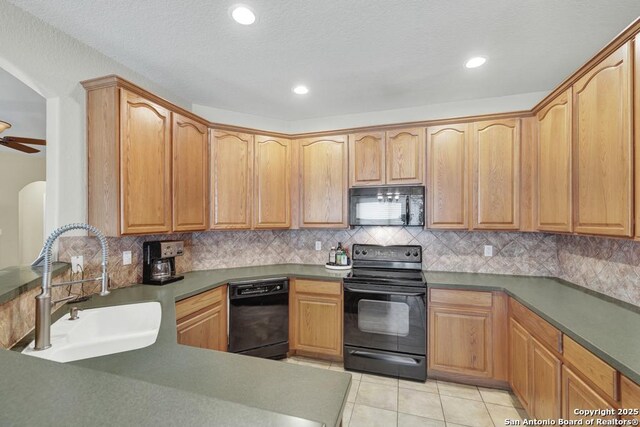kitchen with a sink, black appliances, light tile patterned floors, backsplash, and recessed lighting