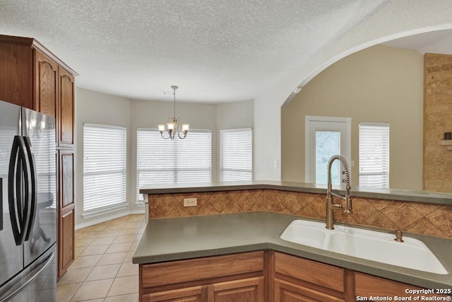 kitchen featuring brown cabinets, freestanding refrigerator, a wealth of natural light, and a sink
