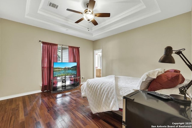 bedroom with hardwood / wood-style flooring, a tray ceiling, baseboards, ornamental molding, and visible vents