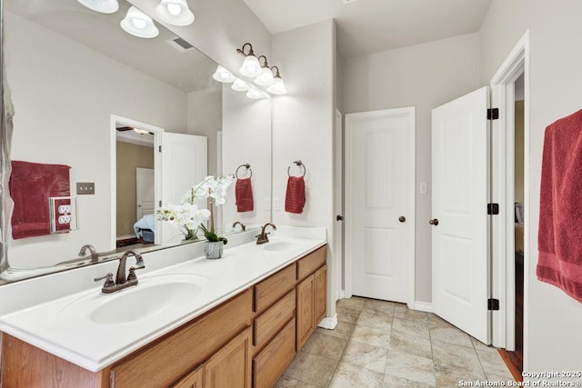 bathroom featuring visible vents, a sink, double vanity, and connected bathroom
