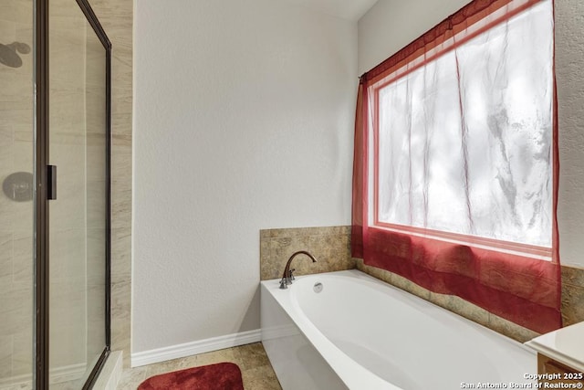 full bathroom with a garden tub, baseboards, and a stall shower