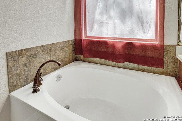 full bath with a garden tub and a textured wall