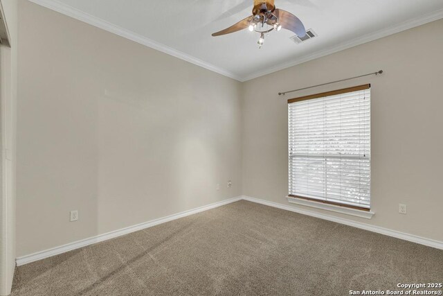 carpeted spare room featuring visible vents, baseboards, ceiling fan, and crown molding