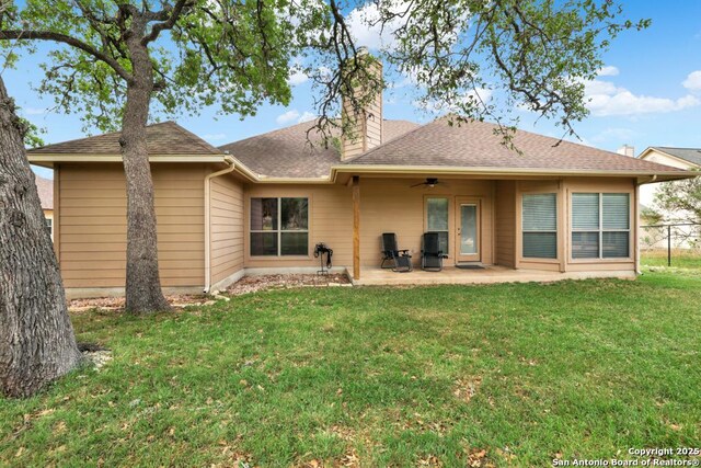 rear view of property featuring a chimney, a lawn, a ceiling fan, fence, and a patio