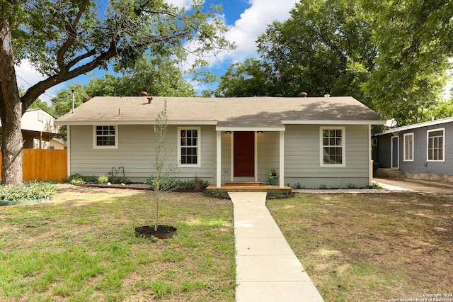 view of front of house with fence, a shingled roof, and a front yard