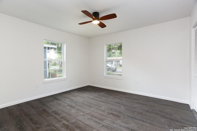 spare room featuring baseboards, a ceiling fan, and dark wood-style floors