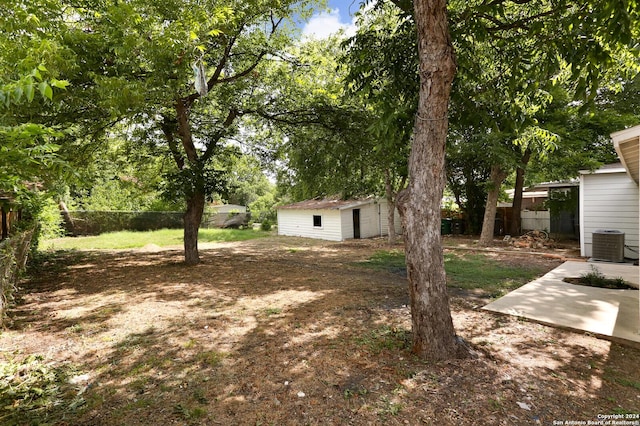 view of yard with fence, an outbuilding, and central AC