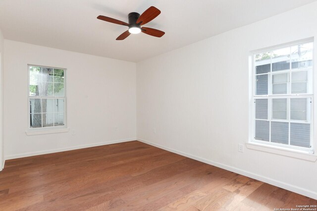 empty room featuring light wood-type flooring, a wealth of natural light, and baseboards