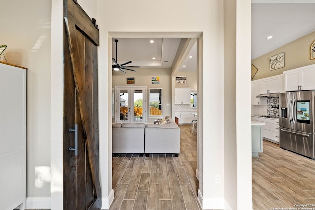 132 Ash Pkwy, La Vernia, TX 78121 - corridor with light wood finished floors, a tray ceiling, recessed lighting, and a barn door