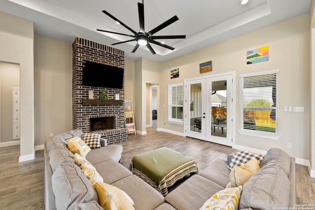 living room featuring ceiling fan, baseboards, wood finished floors, and a raised ceiling