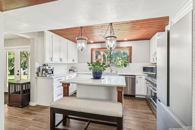 kitchen with white cabinets, stainless steel appliances, light countertops, wood finished floors, and tasteful backsplash