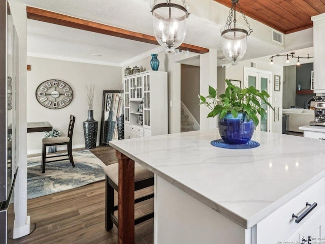 kitchen featuring a center island, light stone counters, visible vents, white cabinetry, and dark wood-style floors