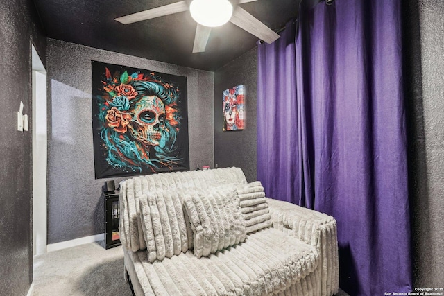 carpeted bedroom featuring a ceiling fan, baseboards, and a textured wall