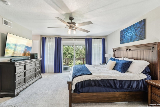 bedroom featuring a textured ceiling, visible vents, a ceiling fan, and light carpet