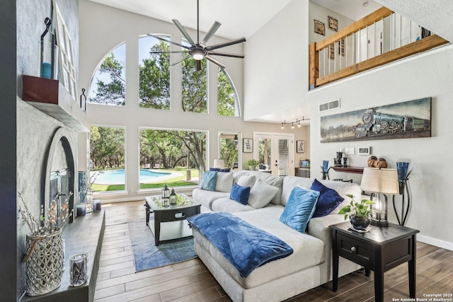 living room featuring plenty of natural light, wood finished floors, visible vents, a ceiling fan, and high vaulted ceiling